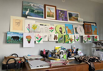 Leona Russell's independent living apartment filled with art supplies and paintings.