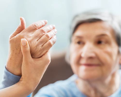 Nurse holding the hand of a woman with arthritis.