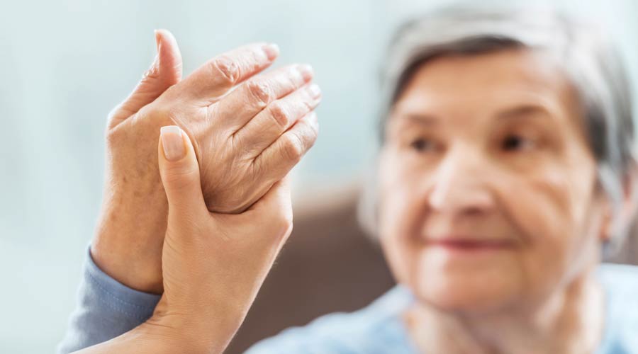 Nurse holding the hand of a woman with arthritis.