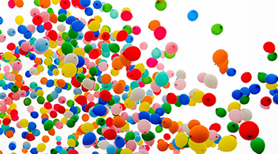 Lots of colorful balloons floating into the air.