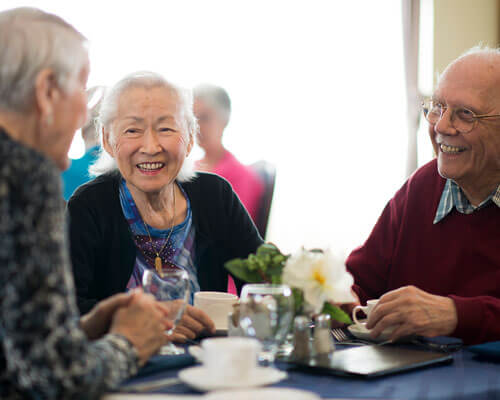 Three people laughing and chatting at a dinner table.
