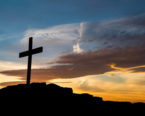 Cross in front of a sunset.