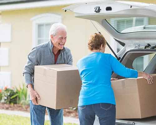 Two people loading boxes into the trunk of a car.