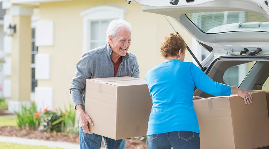 Two people loading boxes into the trunk of a car.
