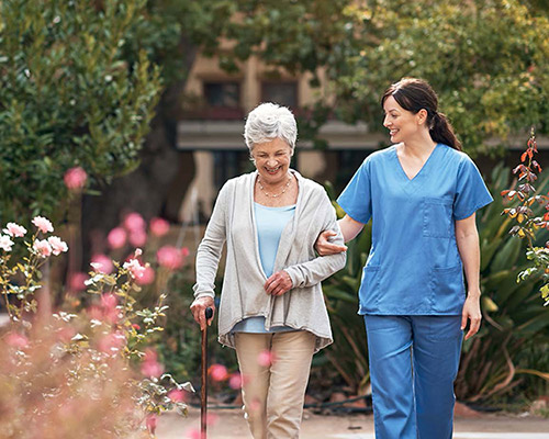 Nurse walking with resident outdoors.