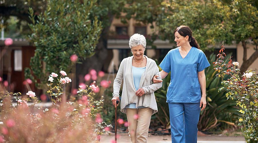 Nurse walking with resident outdoors.