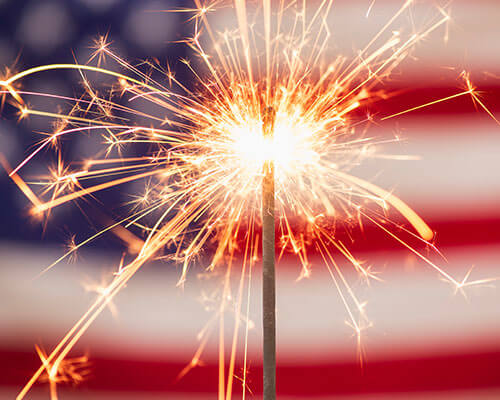 Sparkler in front of an American flag.