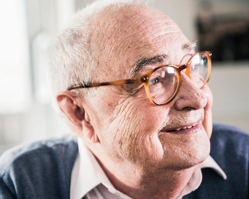 Older man with glasses smiling.