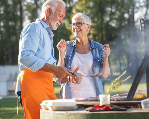 Man and woman cooking food on the grill.