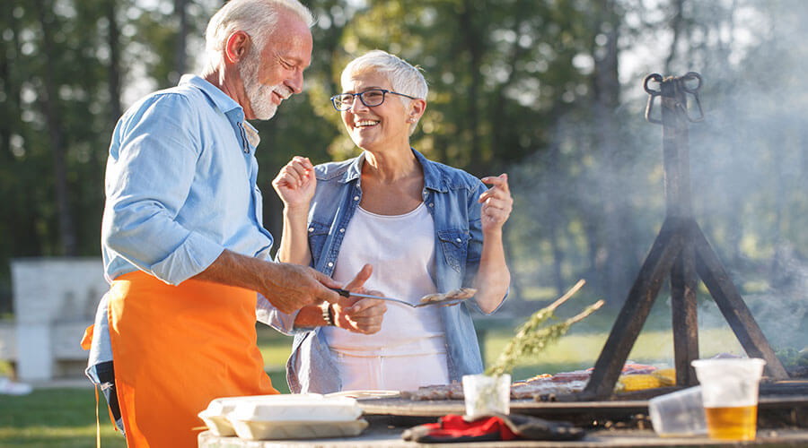 Man and woman cooking food on the grill.