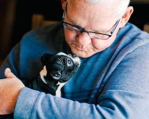 Senior man holding a puppy.
