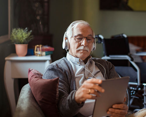 Older man with headphones and a tablet.