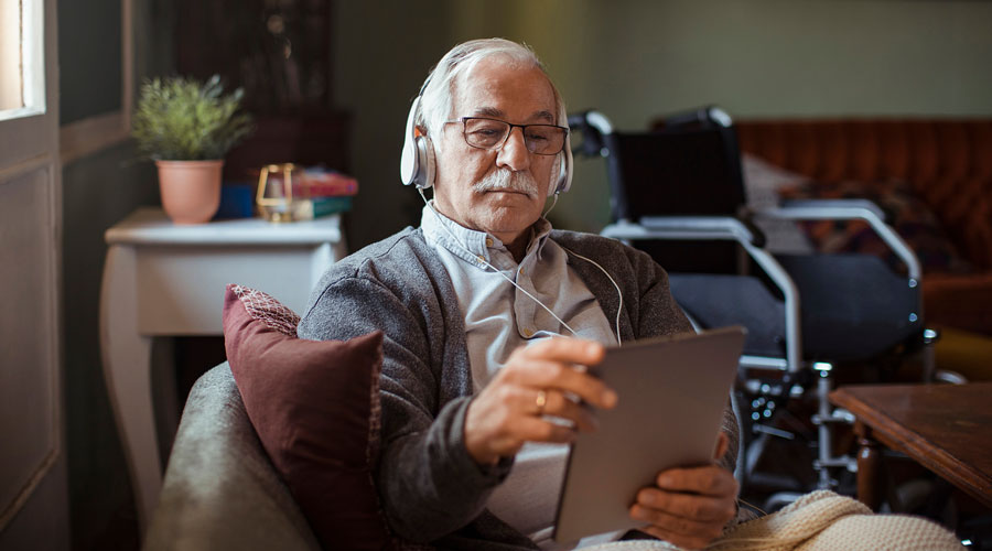 Older man with headphones and a tablet.