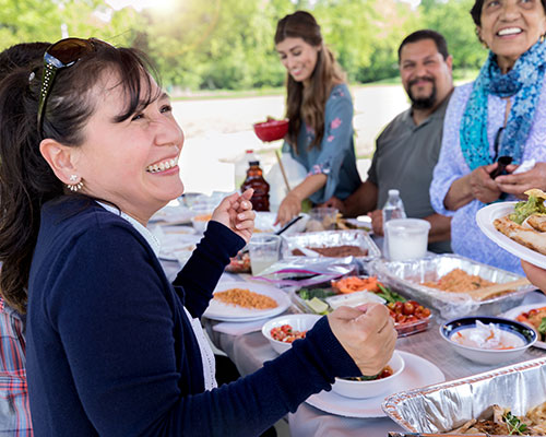 Group of people eating at a picnic.