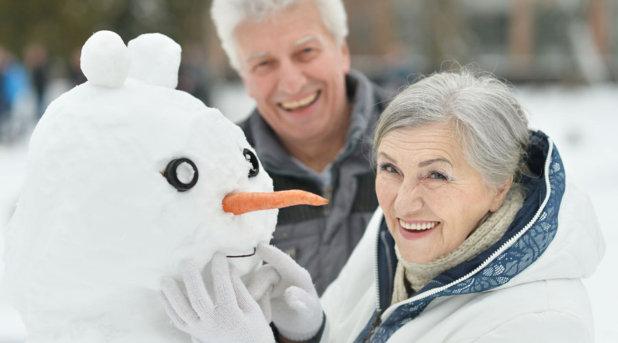 Senior couple building a snowman.