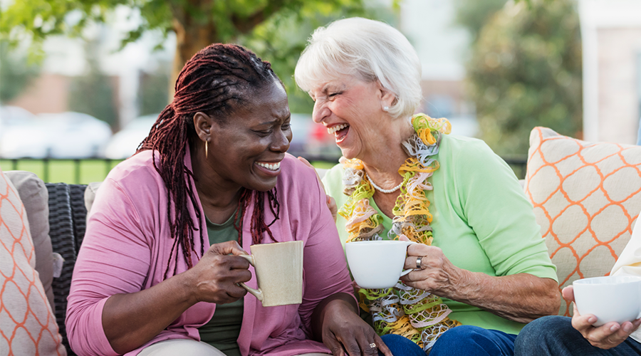 Two ladies laughing while drinking tea.