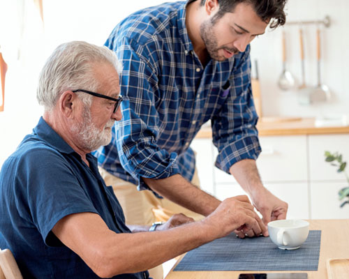 Two men doing a craft at a kitchen table.