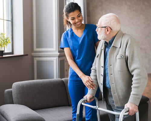 Nurse helping a man with a walker.