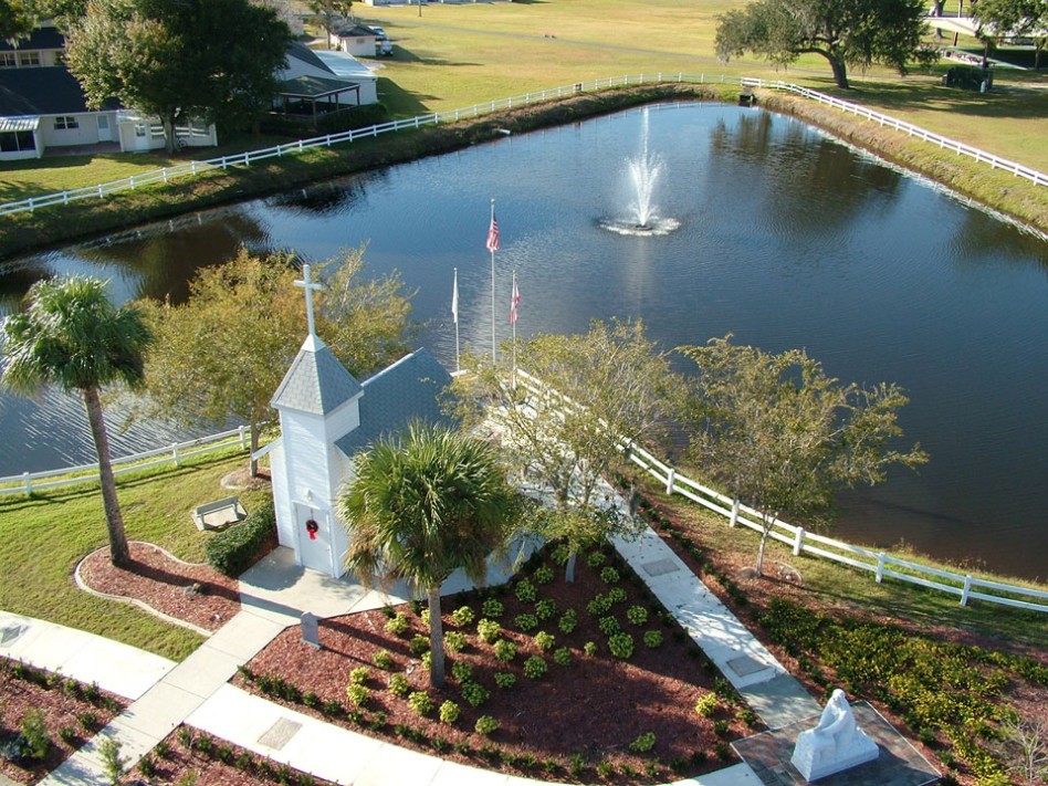Aerial view of Good Samaritan Society - Kissimmee Village chapel with lake stretched out behind it.