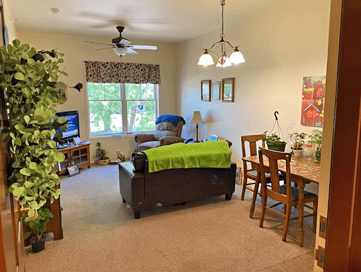 Timber Ridge Assisted Living apartment living room and dining room with a loveseat, chair and tv stand and extra space for a table.