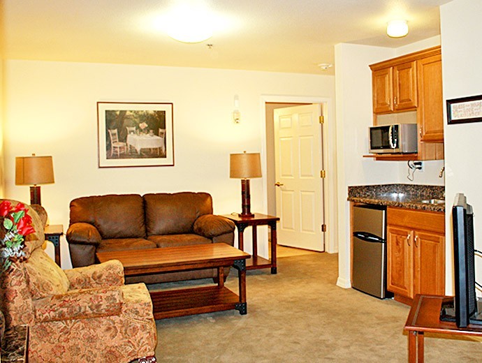 Cozy one-bedroom assisted living apartment living room with kitchenette at Good Samaritan Society - Willow Wind in Prescott, Arizona.