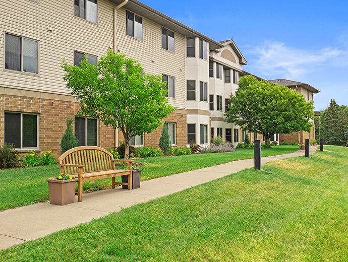 A walking path with beautifully crafted wood benches weaves around the senior living community, Good Samaritan Society - Heritage Place of Roseville in Roseville, MN
