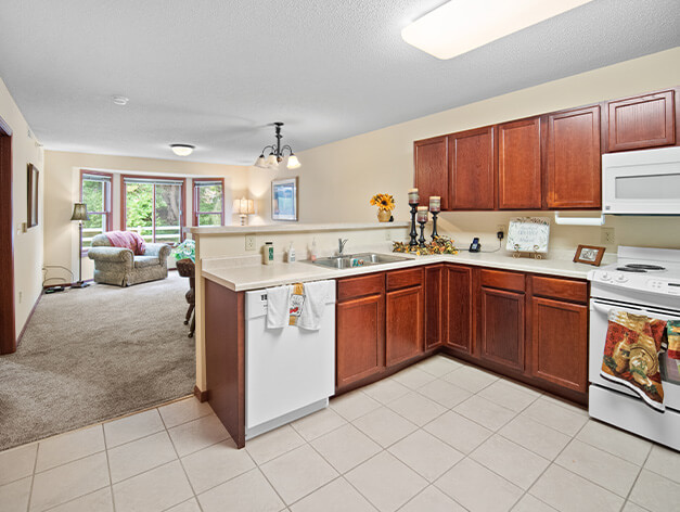 Independent living residents can enjoy the full-size kitchen with an open-concept view of the living room at Good Samaritan Society - Heritage Place of Roseville in Roseville, Minnesota.
