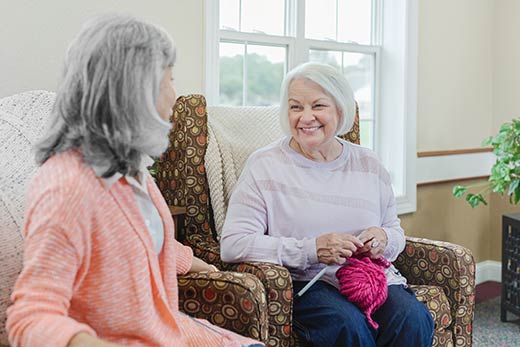 Two women sitting and knitting.
