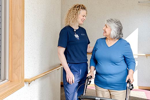Nurse chatting with a senior in the hallway.