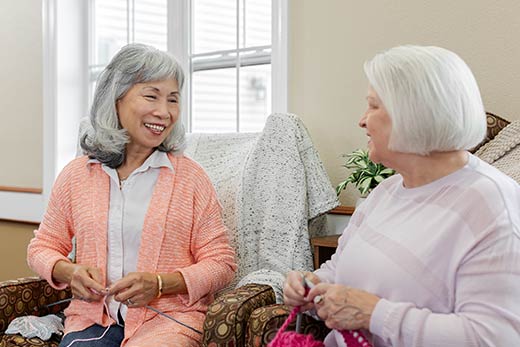 Two women sitting and knitting.