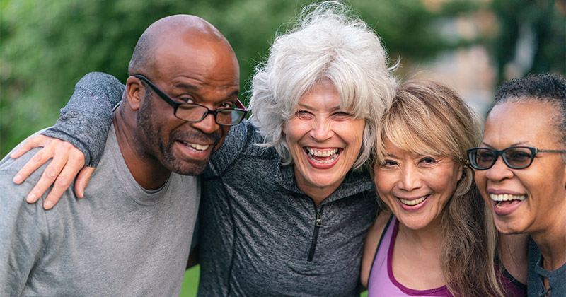 4 people smiling with their arms around each other.