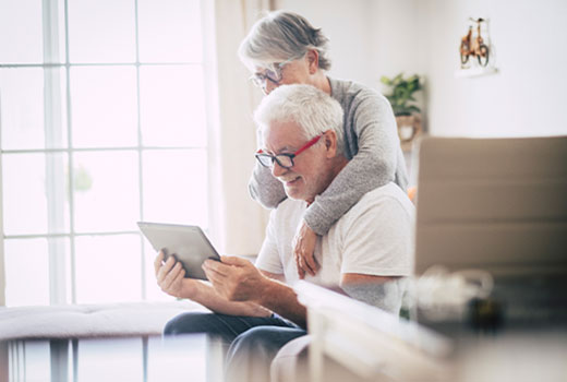 Senior couple smiling as they video chat a grandchild.