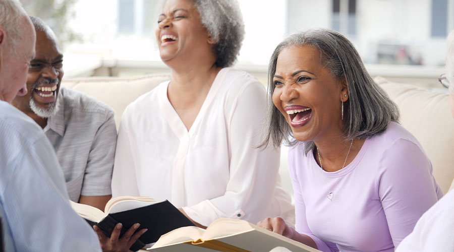 Group of older adults laughing and enjoying conversation at a church service.