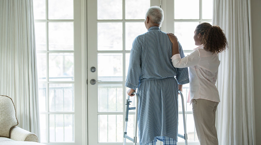 Elderly gentleman and home health caregiver looking out the patio window.