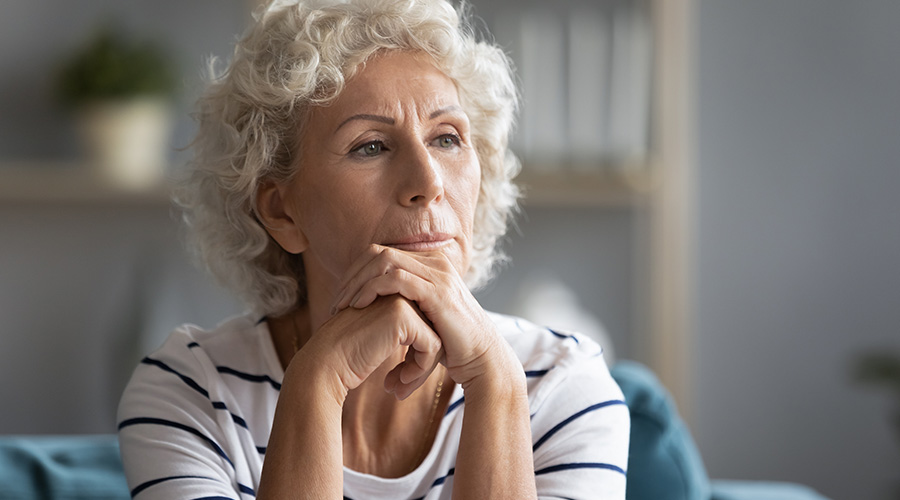 Senior woman contemplating a decision as she sits on the couch.