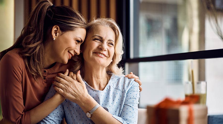 Senior resident embracing a smiling staff member.