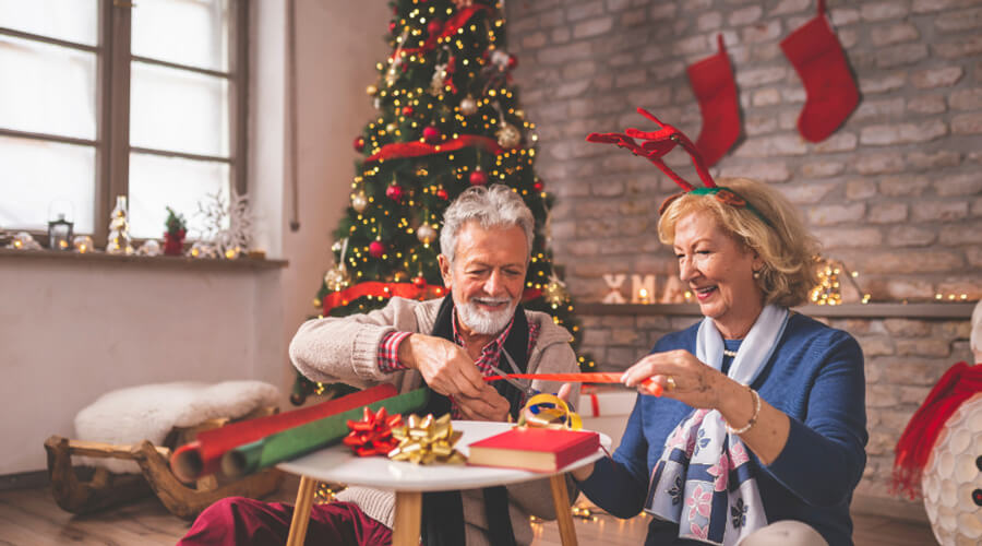 Senior couple smiling as they wrap Christmas presents together.