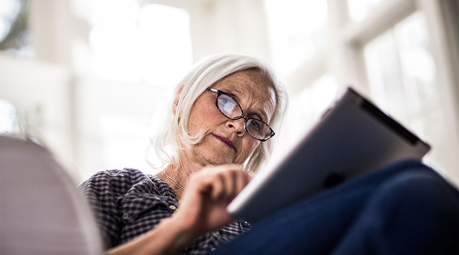 Senior woman sitting on the couch using her iPad