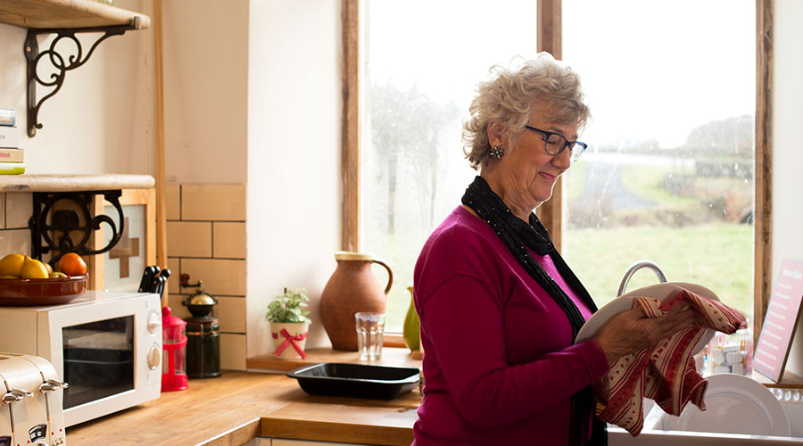 Senior woman drying dishes.