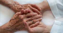 Closeup of senior person's hands being held by a young person