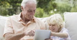 grandfather looks at tablet with young grandson