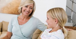 Grandmother sitting on couch listening to young granddaughter talk