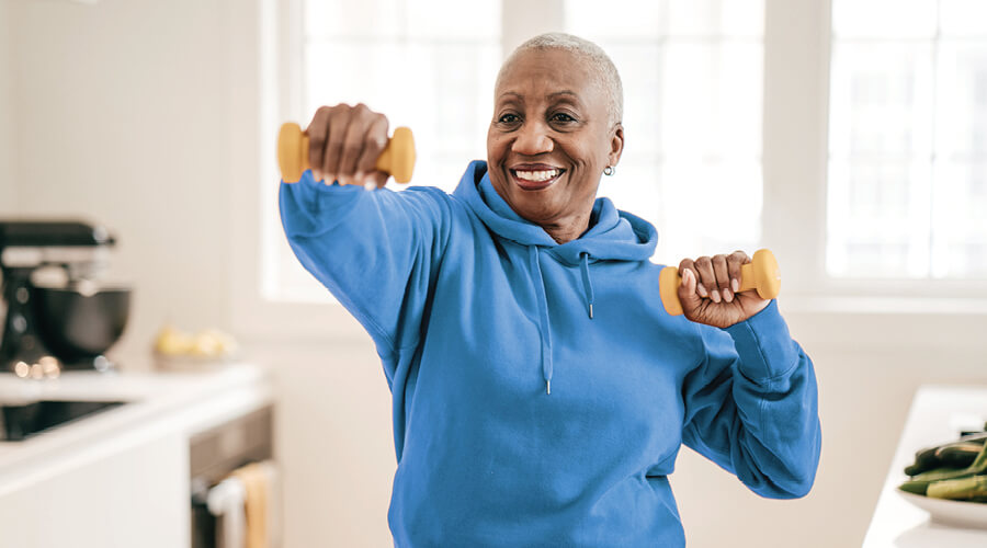 Senior woman exercising at home with light weights.