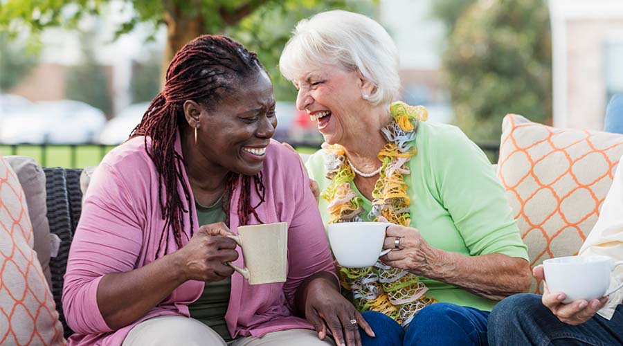 Two women laughing while holding cups of coffee