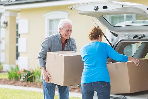 Two people loading boxes into a car.