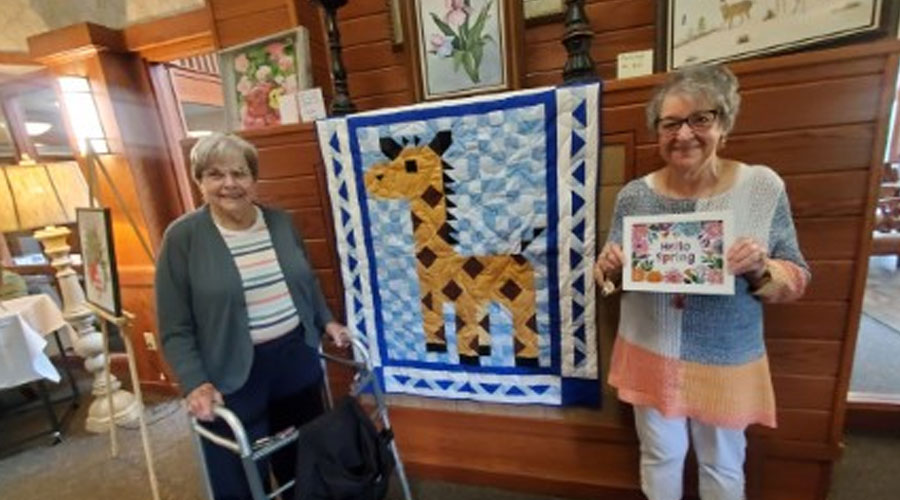 Two senior residents show off their quilt and artwork at the art fair.