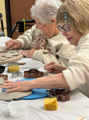 2 women making clay decorations.