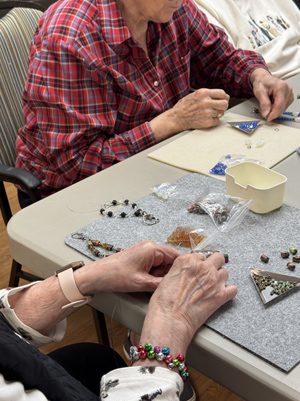 Seniors making keychains with beads.