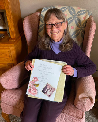 Joan Watson holding a binder with letters from her husband.
