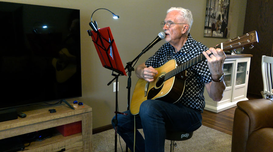 Ken Robinson playing his guitar and singing.